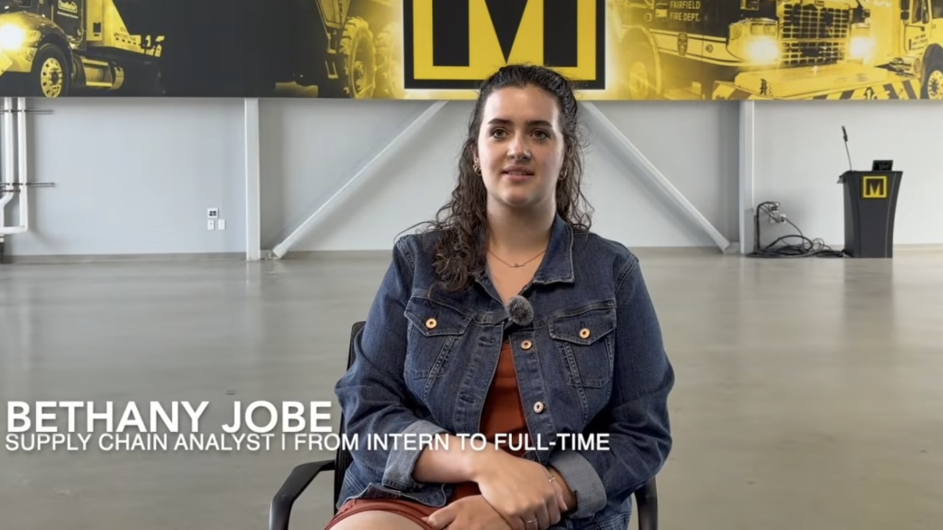 Bethany Jobe - Supply chain analyst - seated for an interview. There is a large Marion banner in the background.